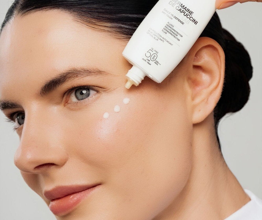 Woman applying Daily Hi-Defense SPF50 Mineral fluid to her cheek