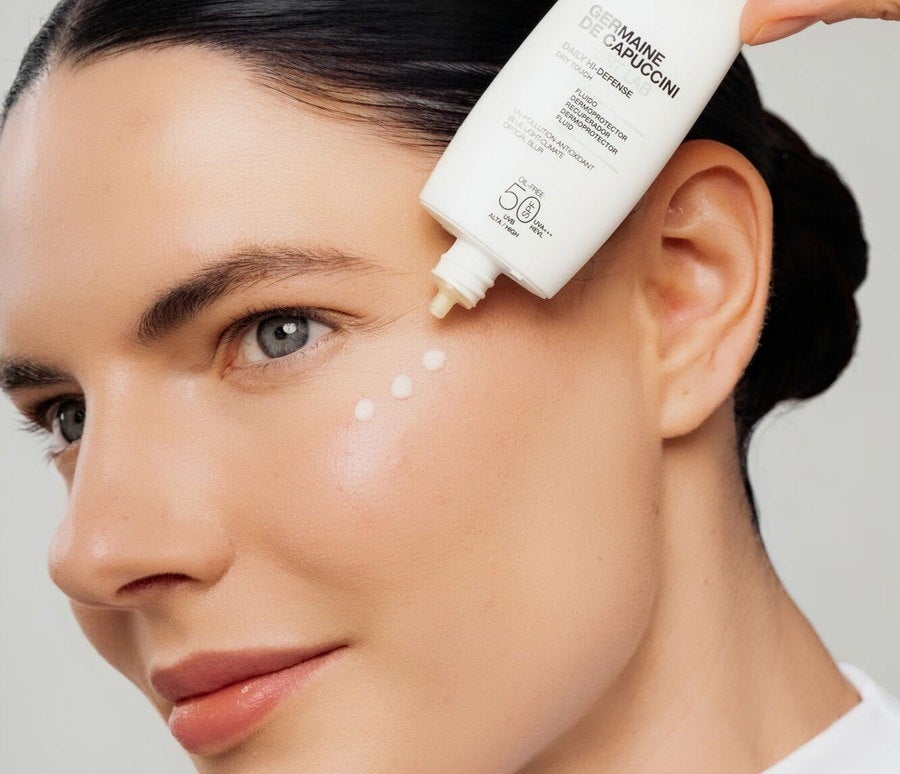 Woman applying Daily Hi-Defense SPF50 Mineral fluid to her cheek